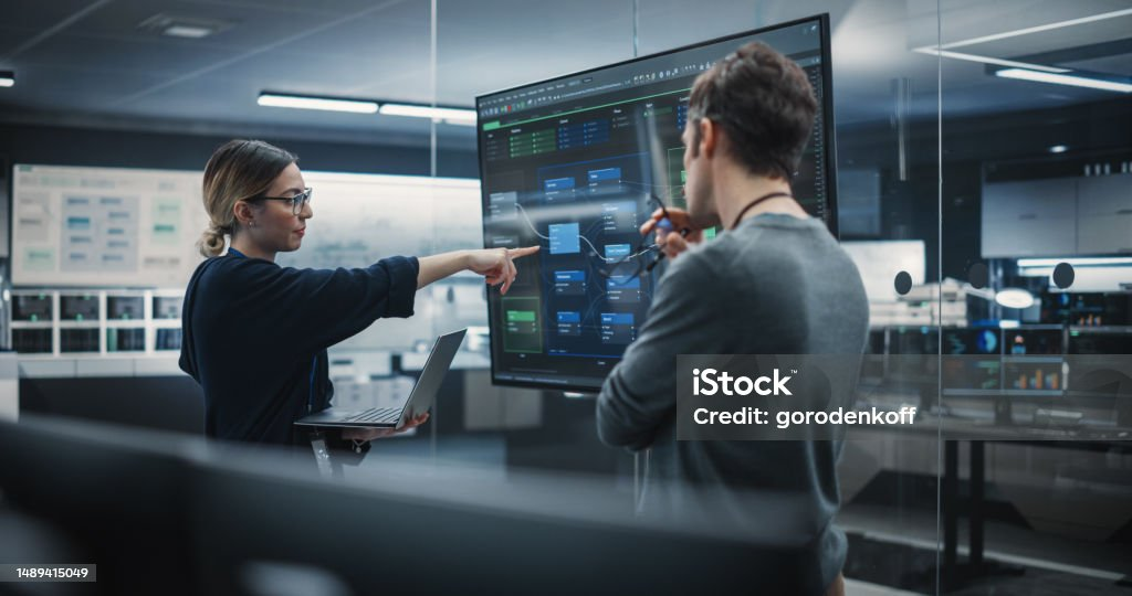 Zwei Personen besprechen ein Netzdiagramm auf einer großen Bildwand